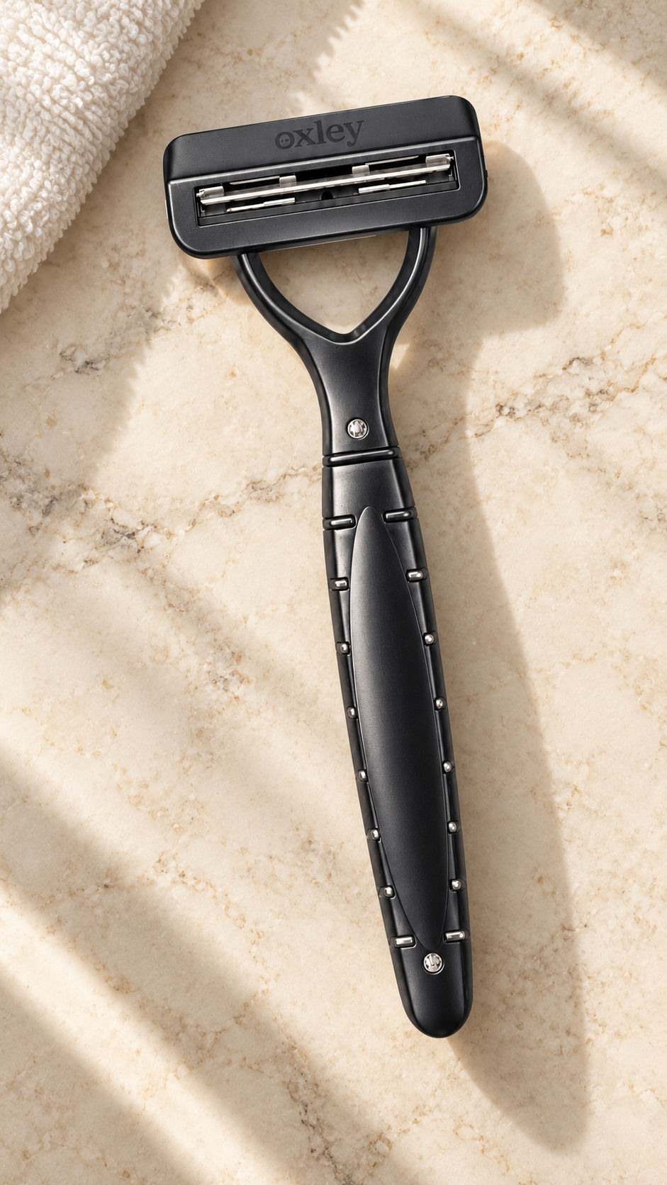 Oxley graphite razor on a marble bathroom counter beside a folded towel